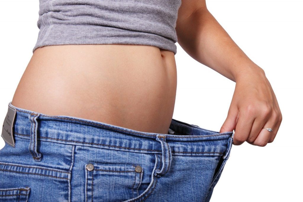 Mujer delgada estirándose los pantalones, de unas cuantas tallas mas grande.