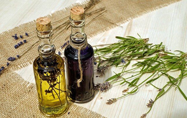 2 botellitas de aceites e flores y unas flores cortadas de lavanda encima de una mesa
